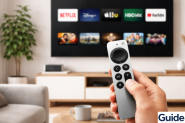 Modern living room with wall-mounted flat-screen TV showing streaming apps and a person holding an Apple TV-style remote control, cozy sofa, coffee table, and natural light.